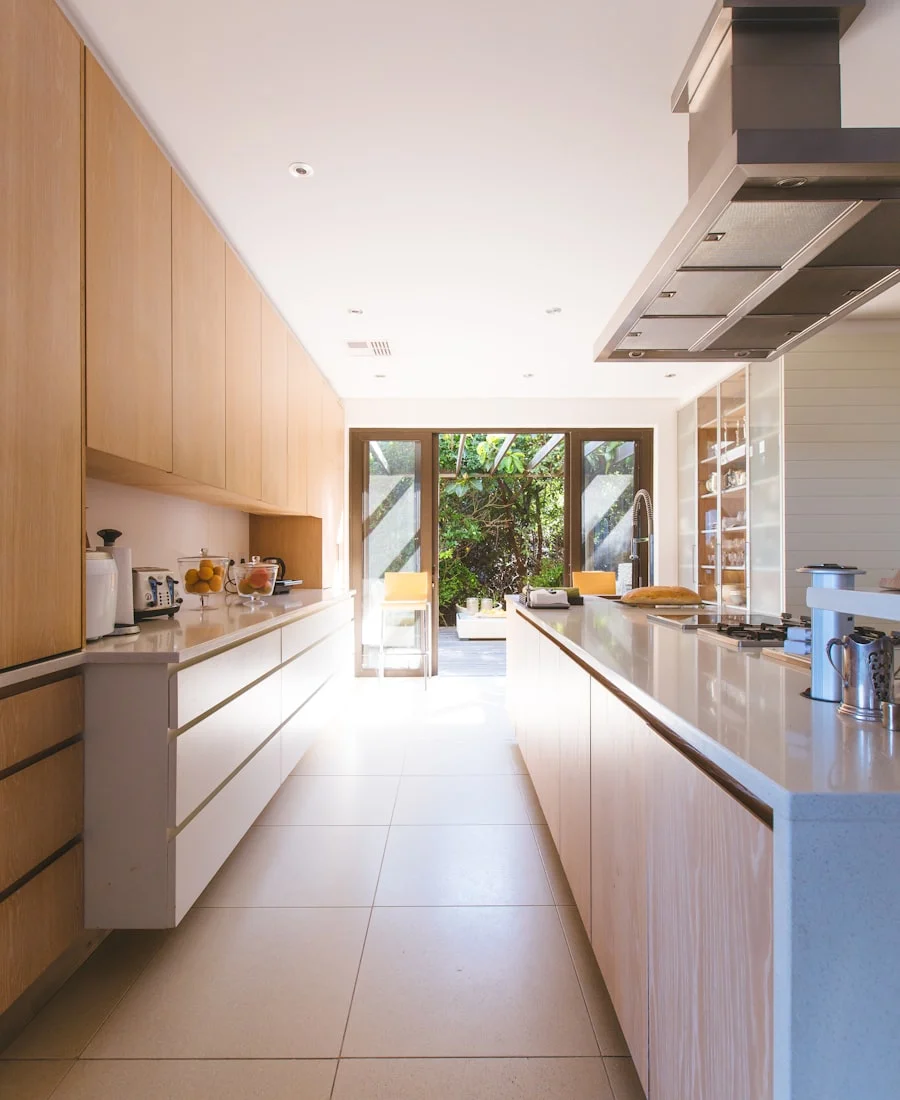 Bright galley kitchen with light oak cabinets and a garden view — representative of the semi-custom product in this illustrative scenario